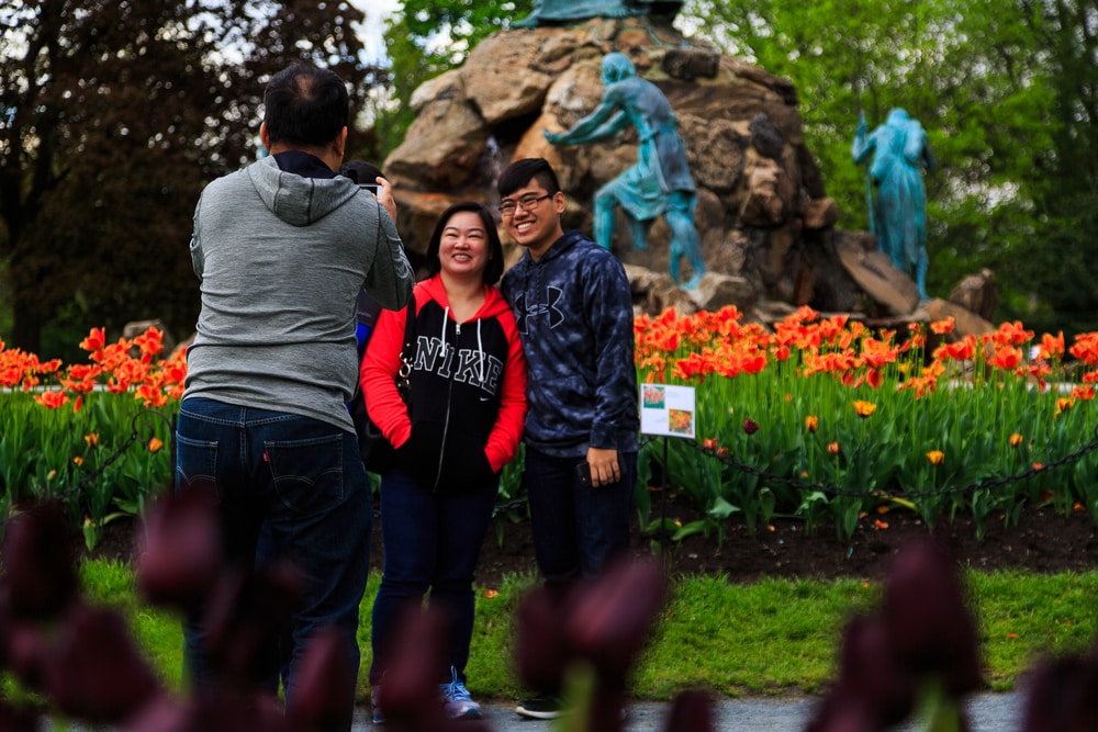 Путешествия: фотография людей, делающих снимок на фоне тюльпанов во время фестиваля в Олбани