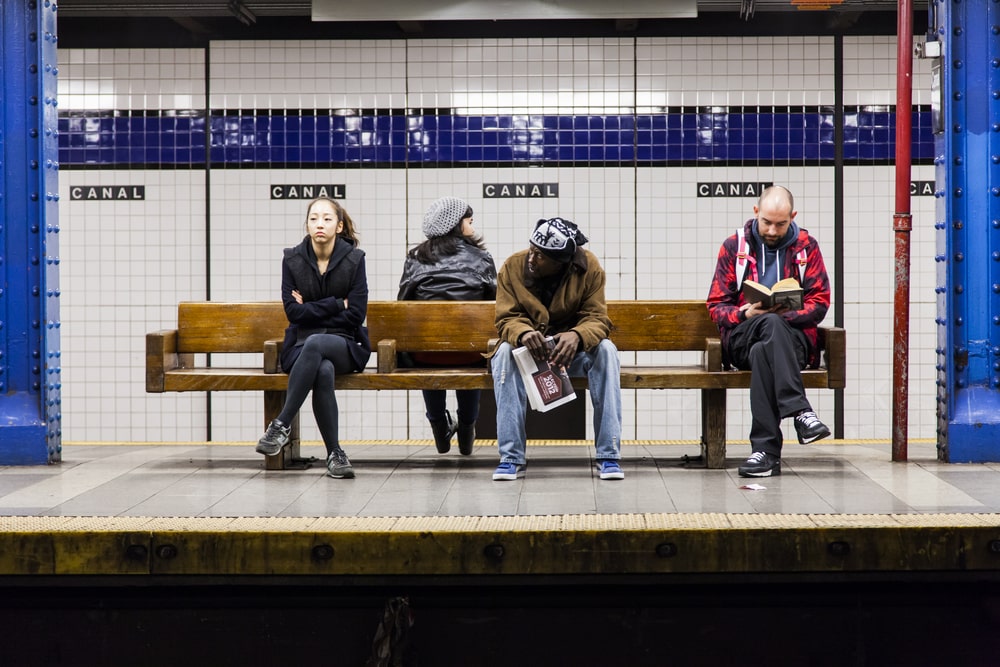 Локальные новости: фотография людей, сидящих на станции метро в Нью-Йорке