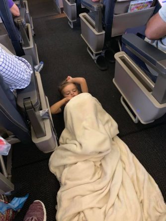 фотография мальчика, лежащего в проходе в самолете