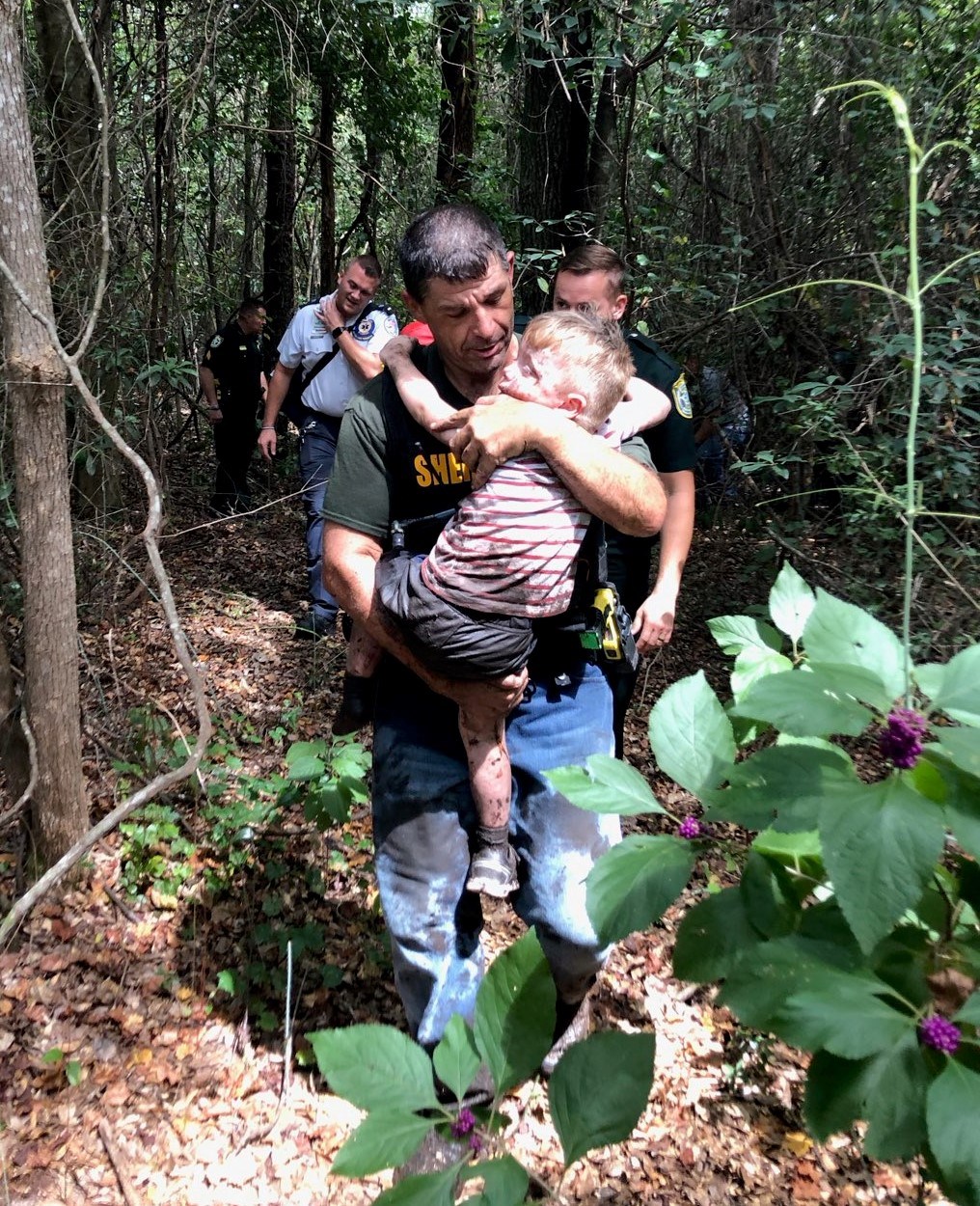 фотография спасателя, выносящего мальчика на руках из леса
