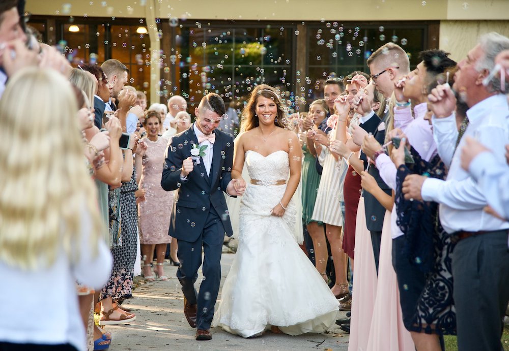фотография жениха с невестой, идущих мимо гостей