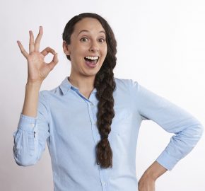 Белая женщина в рубашке с косой показывает жест ОК фото