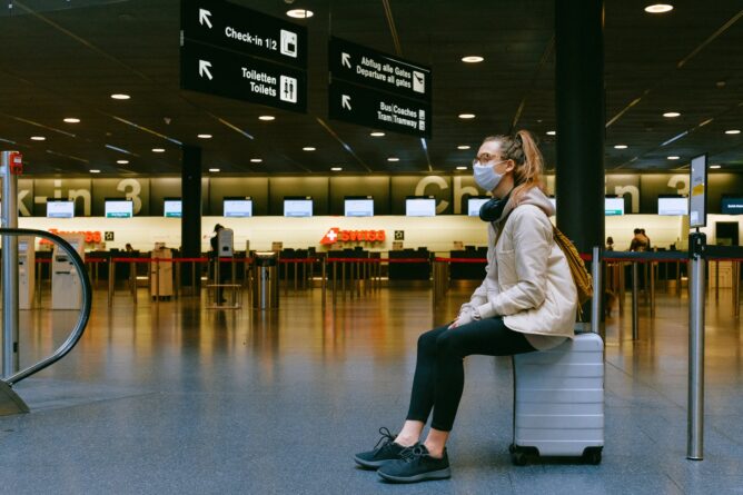 девушка сидит на чемодане в аэропорту