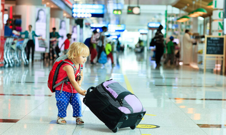 ребенок везет чемодан по аэропорту