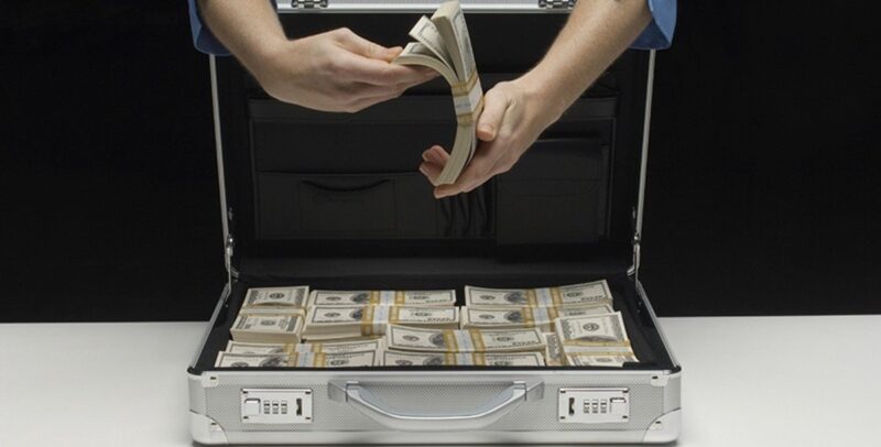 мужчина пересчитывает доллары в чемодане