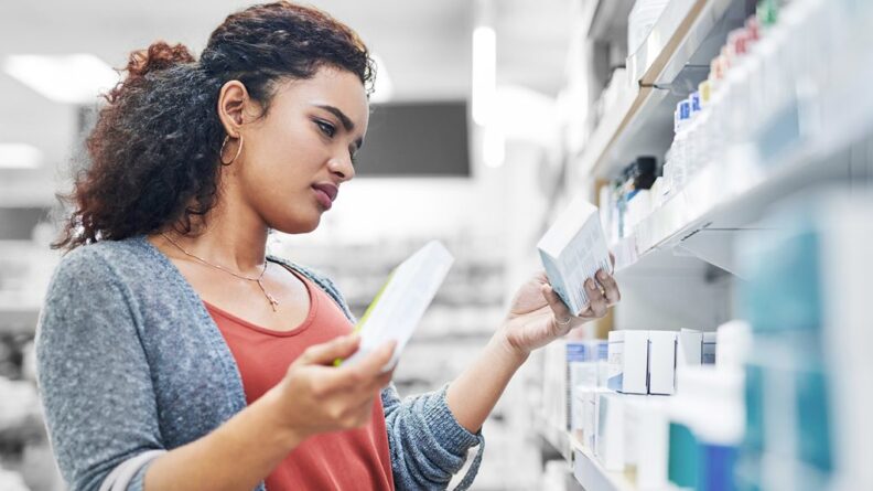 женщина выбирает таблетки в аптеке