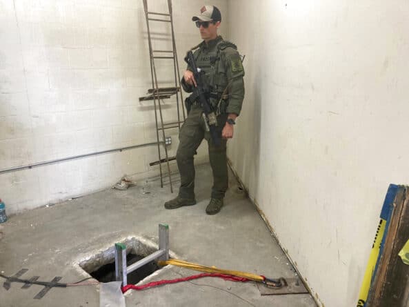 полицейский стоит у входа в подземный тоннель