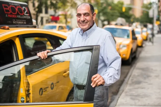 мужчина таксист возле желтого такси