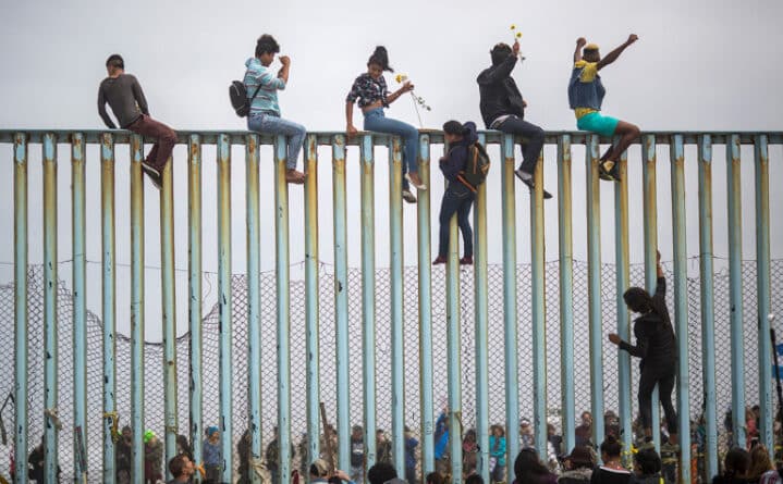 дети сидят на заборе на границе с США
